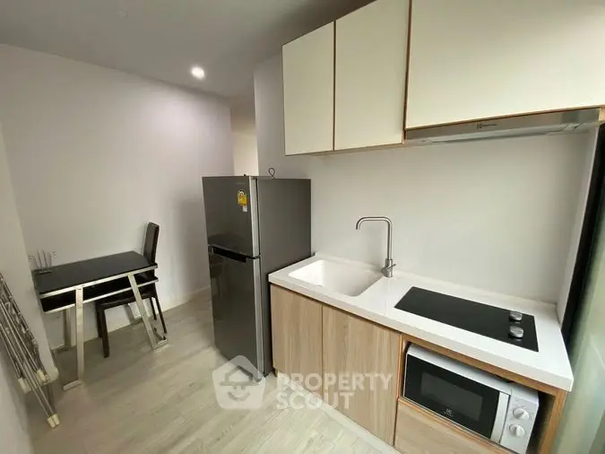 Modern compact kitchen with sleek appliances and dining area in a stylish apartment.