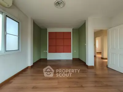 Spacious empty room with wooden flooring and modern design elements