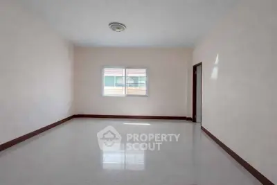 Spacious empty room with large window and tiled floor, perfect for customization.