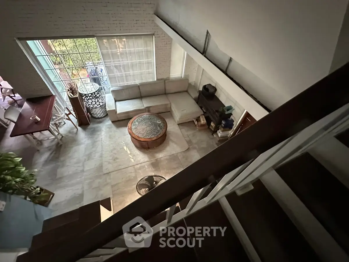 Spacious living room with high ceiling and large windows offering natural light and garden view.