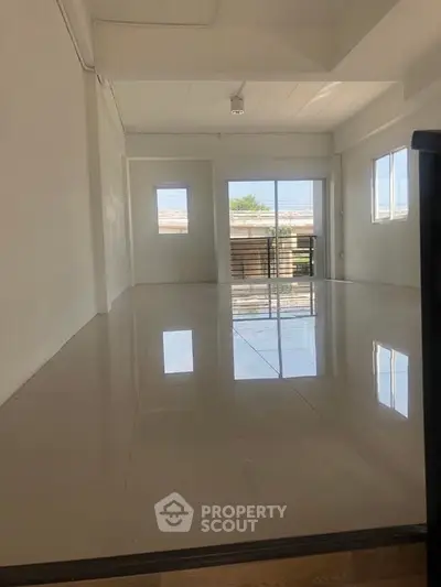 Spacious and bright interior with glossy floors and large windows offering natural light.