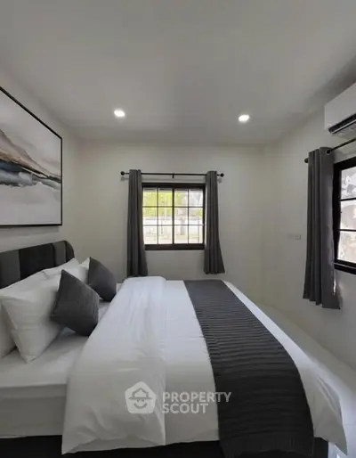 Modern bedroom with stylish decor and natural light, featuring a cozy bed and elegant artwork.