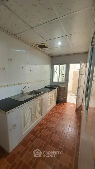 Charming kitchen with tiled walls and floor, featuring a sleek countertop and stainless steel sink.