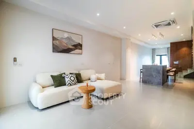 Modern open-plan living room with stylish decor and spacious layout, featuring a cozy sofa and elegant lighting.