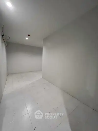 Spacious empty room with white tiled flooring and minimalistic design.