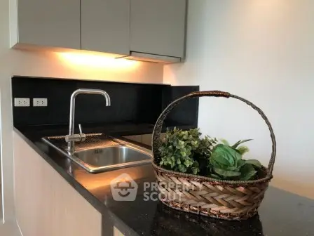 Modern kitchen with sleek black countertop and stylish sink, featuring elegant cabinetry and ambient lighting.