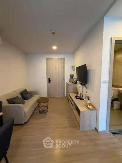 Modern living room with sleek furniture and TV setup in a cozy apartment.