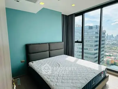 Modern bedroom with large windows offering stunning city views in a high-rise apartment.