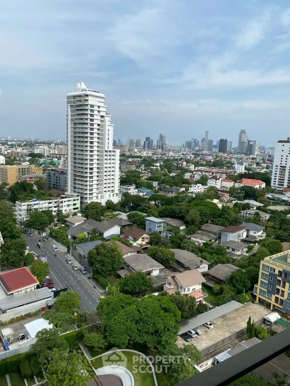 Stunning cityscape view from high-rise balcony overlooking urban skyline and lush greenery.