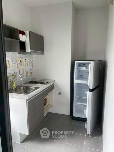 Compact kitchen with modern cabinets and fridge in a cozy apartment setting.