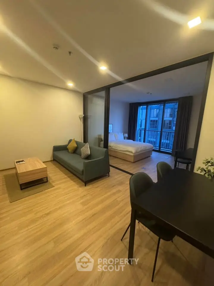 Modern open-plan living room with cozy seating and bedroom view, perfect for urban living.