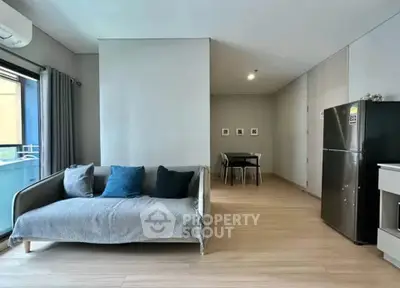Modern living room with cozy sofa and dining area in open layout apartment.