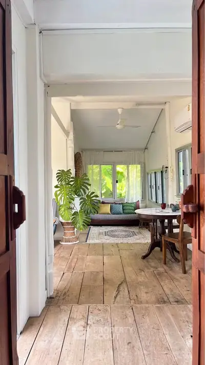 Charming living room with rustic wooden floors and lush greenery view.