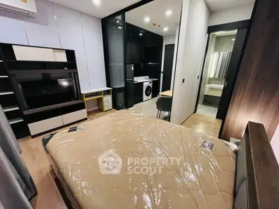 Modern bedroom with sleek design, featuring a TV unit and a glimpse of a stylish bathroom.