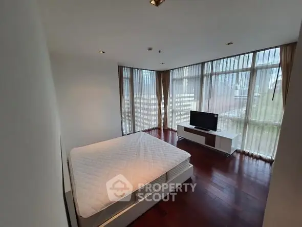 Spacious bedroom with large windows and modern furnishings in a luxurious apartment.