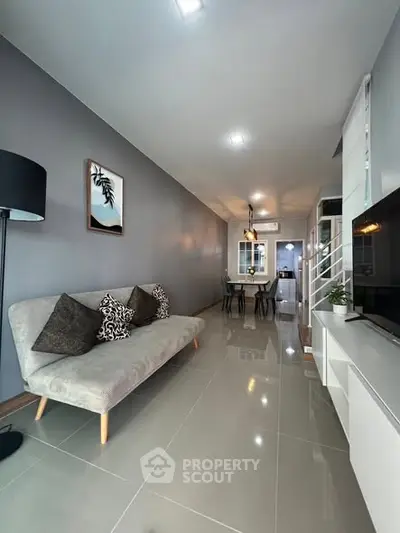 Modern living room with sleek gray decor and open layout, featuring stylish furniture and bright lighting.