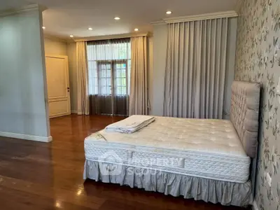 Spacious bedroom with elegant decor and large windows for natural light.