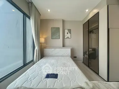 Modern bedroom with large window and stylish decor in a contemporary apartment.