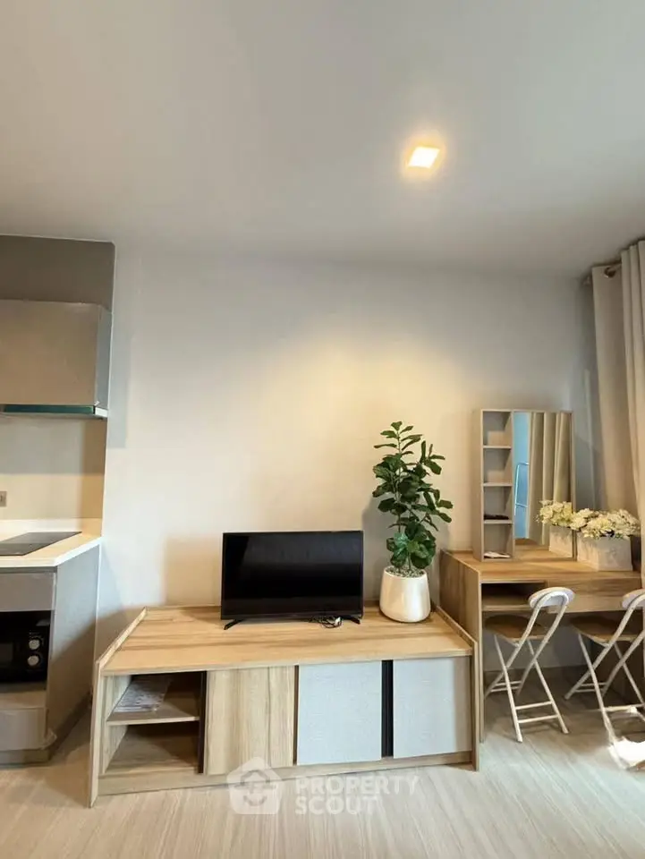 Modern living room with stylish furniture and natural light, featuring a TV stand and a cozy workspace.