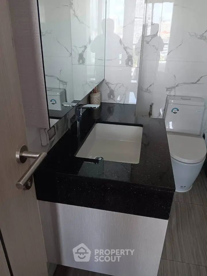 Modern bathroom with sleek black countertop and stylish fixtures in a contemporary apartment.