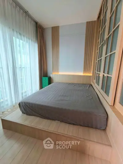 Modern bedroom with platform bed and floor-to-ceiling windows in a stylish apartment.