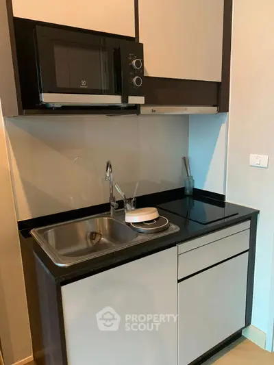 Modern compact kitchen with microwave and sleek cabinetry in a stylish apartment.