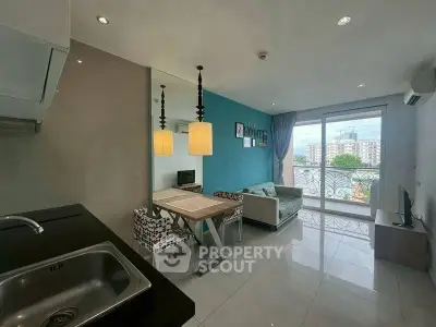 Modern living room with open kitchen and balcony view in urban apartment.