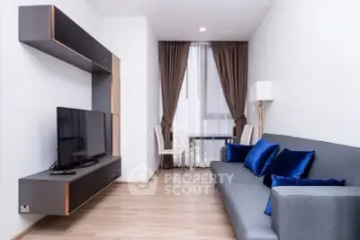 Modern living room with sleek furniture and elegant decor, featuring a wall-mounted TV and stylish blue accents.