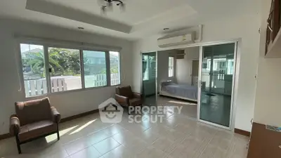 Spacious living room with large windows and sliding doors leading to a cozy bedroom.