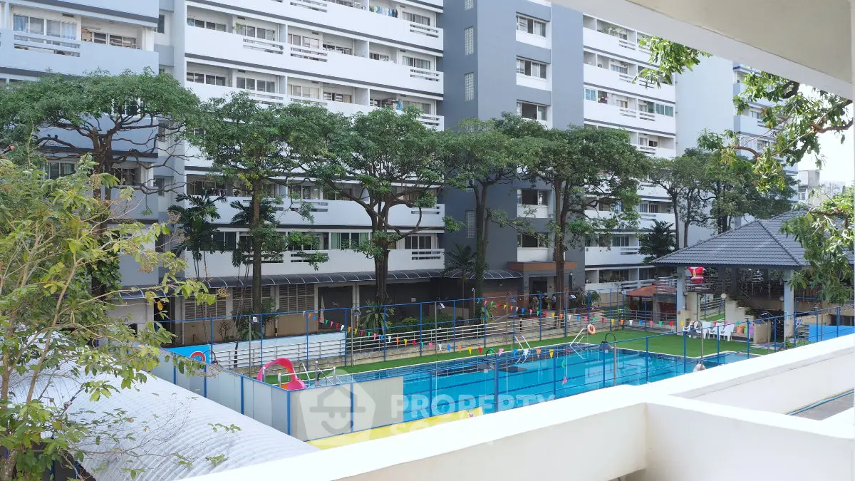 Modern apartment complex with swimming pool and lush greenery, ideal for urban living.