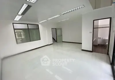 Spacious white-tiled room with modern lighting, ideal for office or studio space.