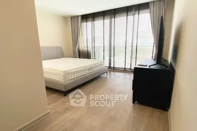 Spacious bedroom with large window and modern furnishings