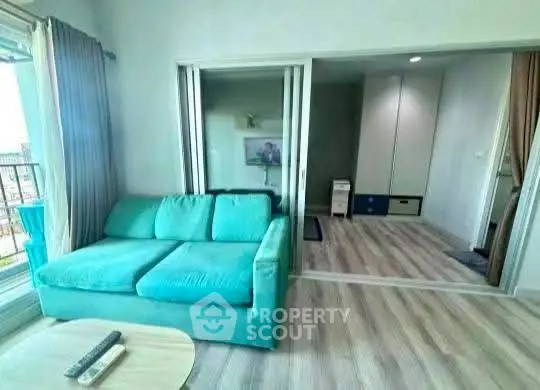 Modern living room with teal sofa and sliding glass doors in bright apartment