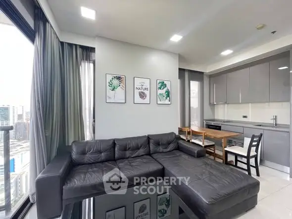 Modern living room with sleek black sofa and stylish kitchen in open layout