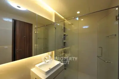 Modern bathroom with glass shower and sleek vanity in luxury apartment.