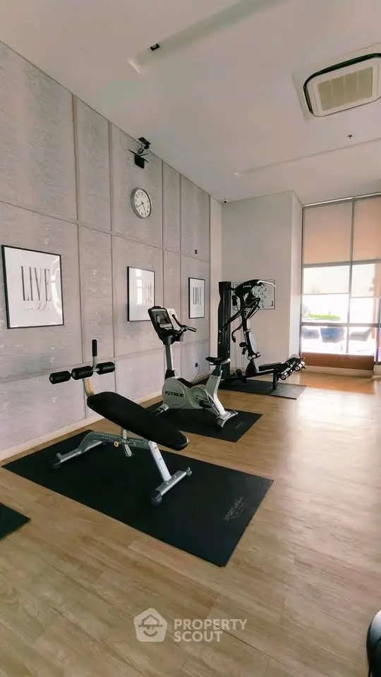 Modern gym with exercise equipment and wooden flooring in a residential building.