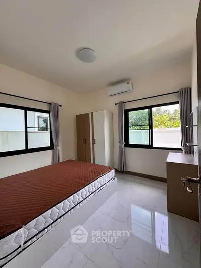 Spacious bedroom with modern furnishings and large windows offering natural light.