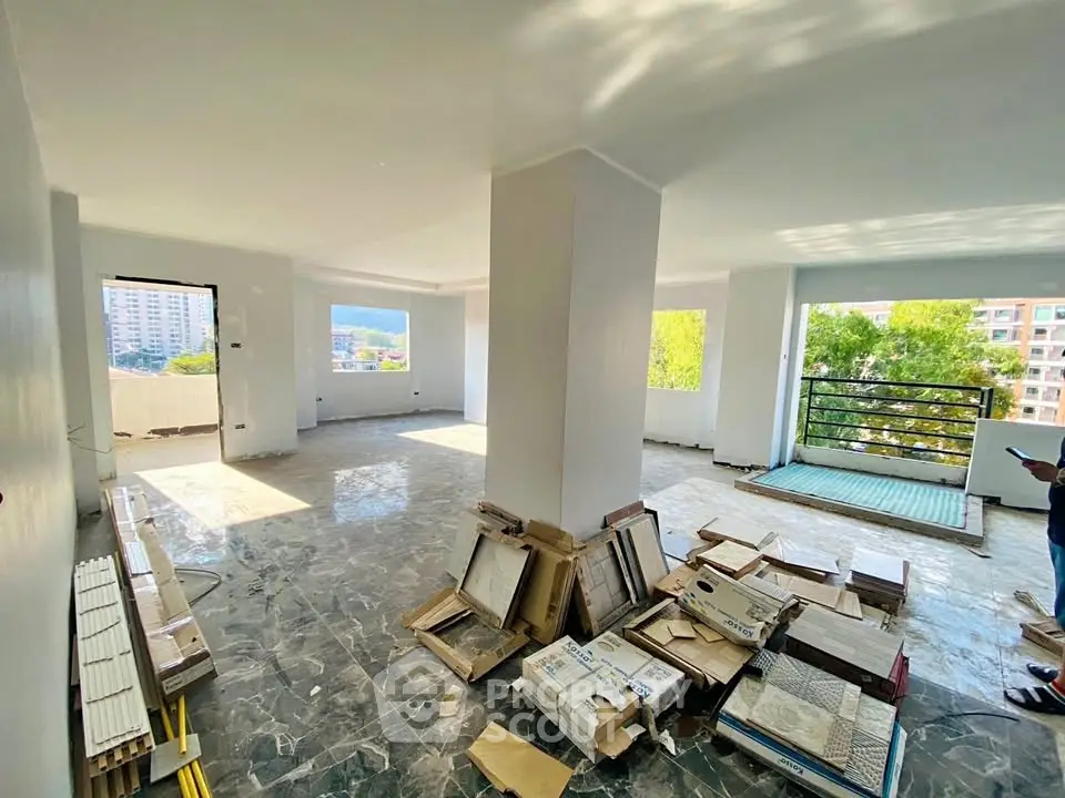 Spacious open-plan living area with large windows and balcony access, ideal for modern living.