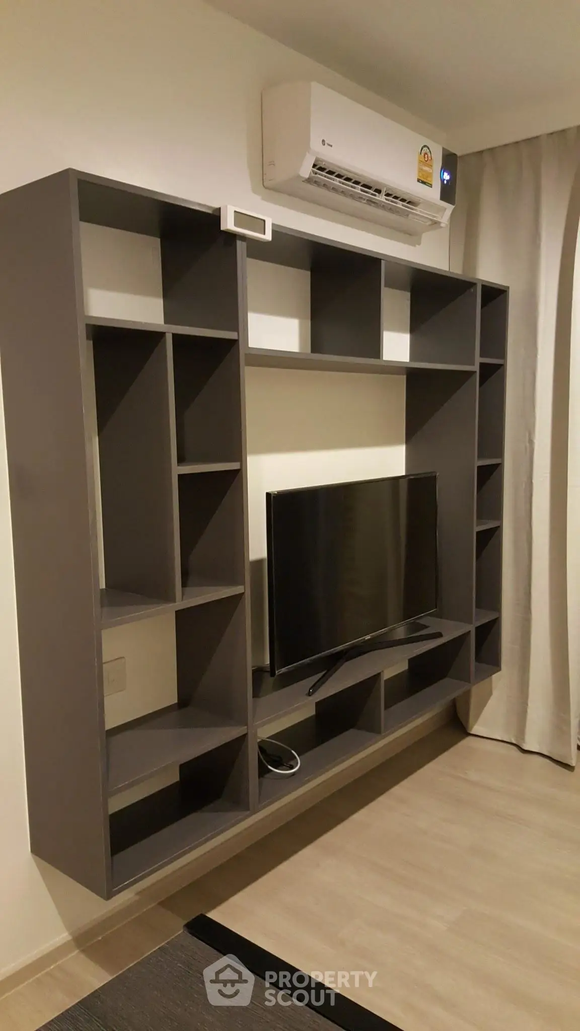 Modern living room with sleek wall-mounted TV and air conditioning unit.