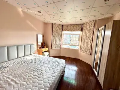 Spacious bedroom with large windows and elegant wooden flooring