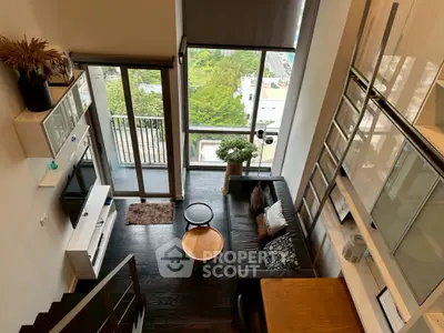 Modern loft apartment with high ceilings, large windows, and stylish interior overlooking cityscape.