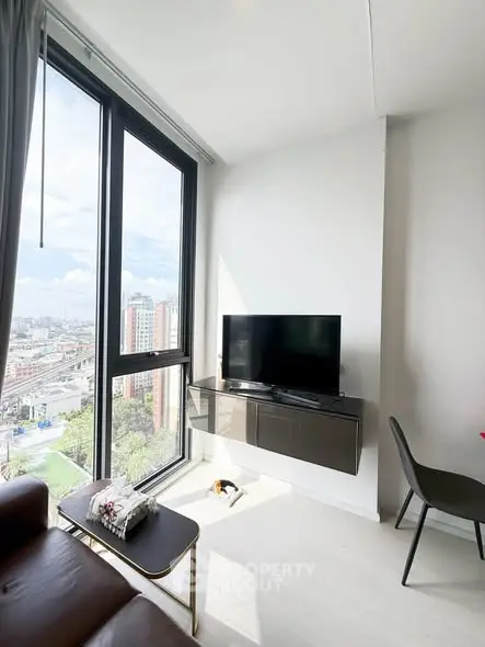 Modern living room with large windows offering stunning city views and sleek furniture.
