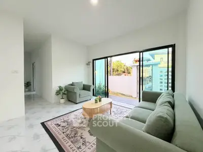 Spacious living room with modern decor and large sliding glass doors opening to a serene outdoor view.