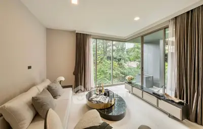 Modern living room with large windows and garden view, featuring elegant decor and neutral tones.