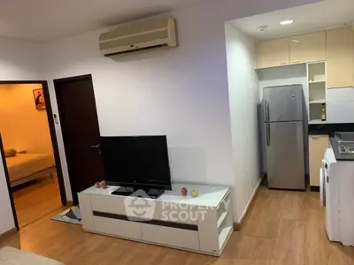 Modern living room with sleek TV stand, air conditioning, and view into cozy bedroom and kitchen.