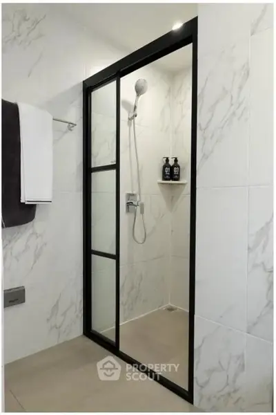 Modern bathroom with sleek shower enclosure and marble tiles.