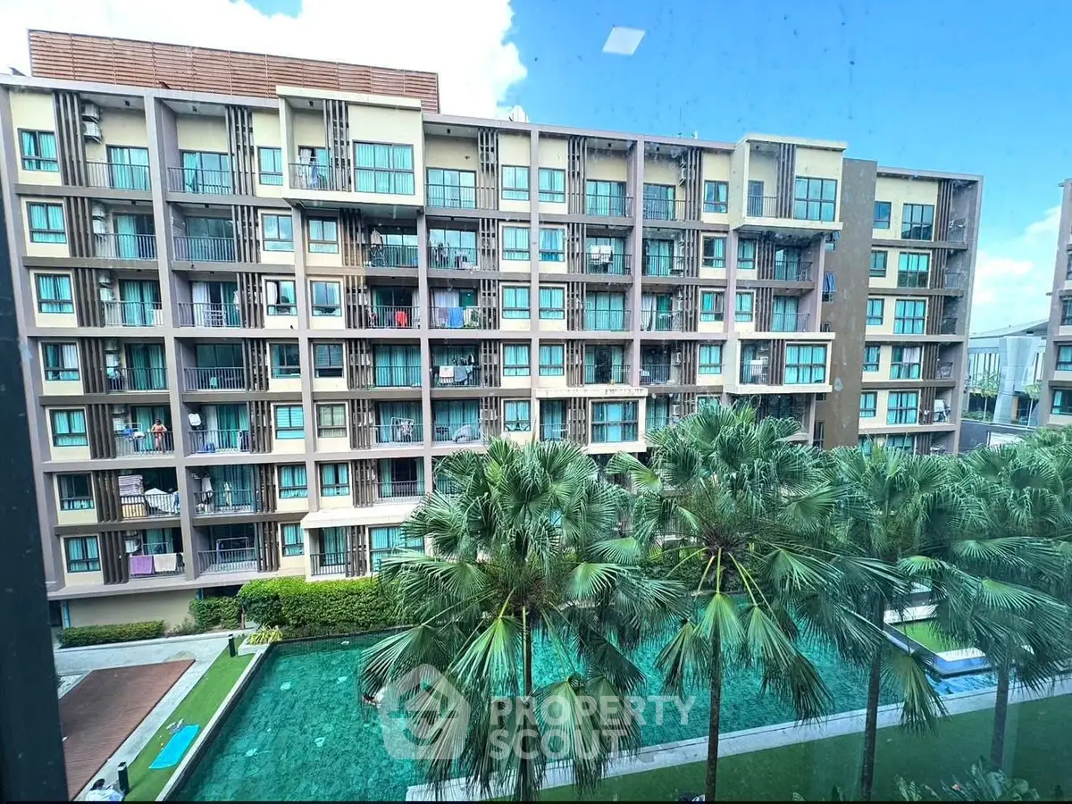 Modern apartment building with pool and palm trees, offering a luxurious lifestyle.