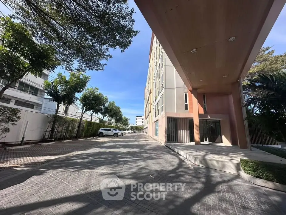 Modern building exterior with spacious parking area and lush greenery