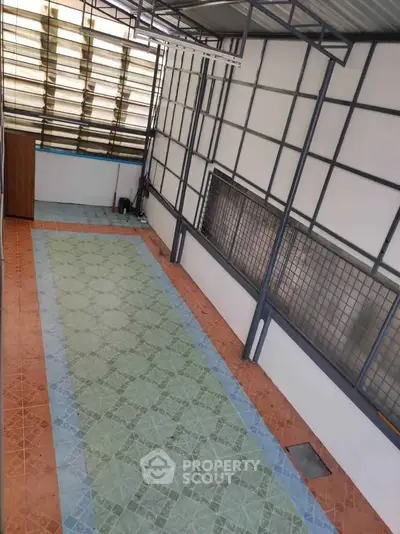 Spacious covered outdoor area with tiled flooring and metal framework, ideal for versatile use.