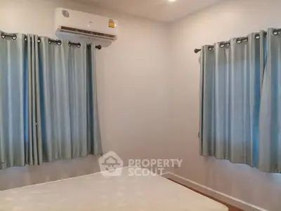 Cozy bedroom with air conditioning and natural light through double windows.